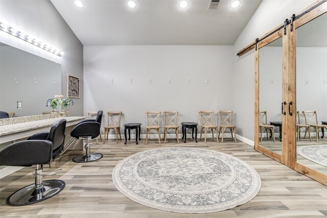 living area featuring a barn door, light hardwood / wood-style floors, and vaulted ceiling