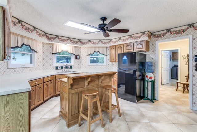 kitchen featuring black refrigerator, a center island, a textured ceiling, and washer / dryer