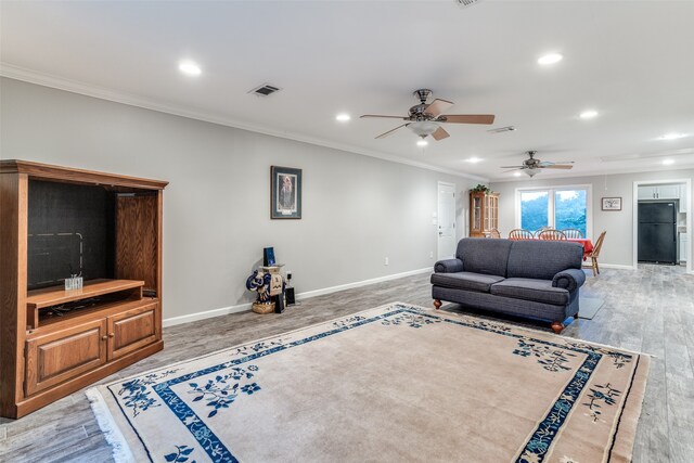 living room with hardwood / wood-style floors, ceiling fan, and crown molding