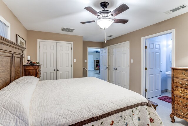 bedroom with ensuite bath, ceiling fan, light carpet, and multiple closets