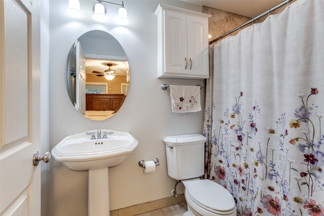 bathroom with tile patterned flooring, toilet, ceiling fan, and curtained shower