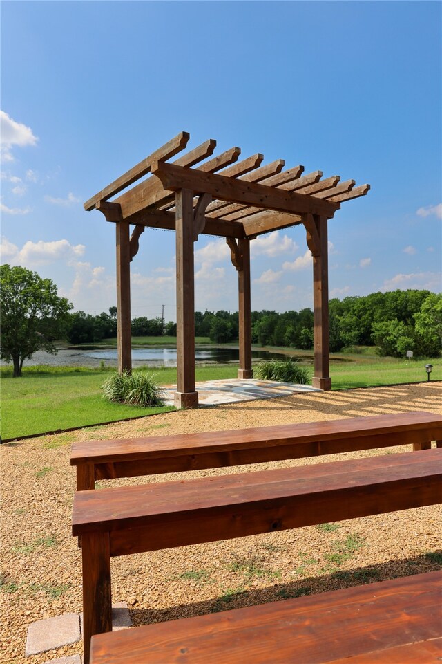 surrounding community with a water view and a pergola