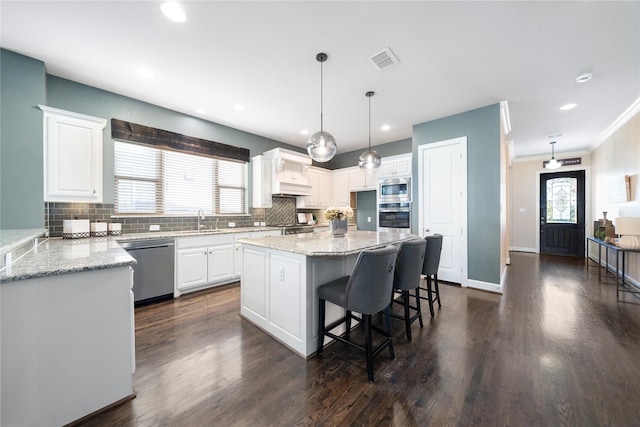 kitchen with premium range hood, white cabinets, dark wood-type flooring, a kitchen island, and decorative backsplash