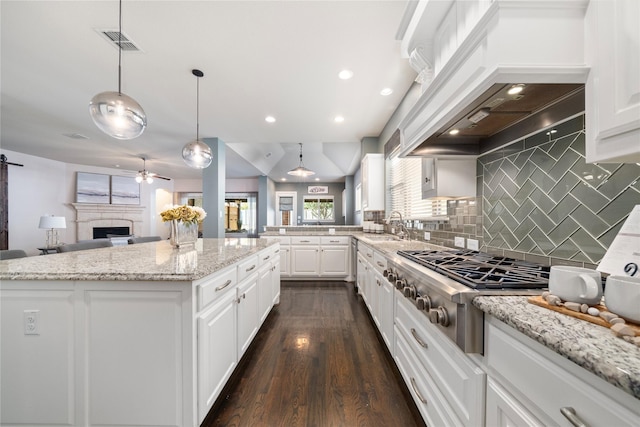 kitchen featuring white cabinets, stainless steel appliances, a center island, and decorative light fixtures