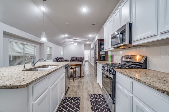 kitchen with sink, white cabinets, a kitchen island with sink, decorative light fixtures, and stainless steel appliances