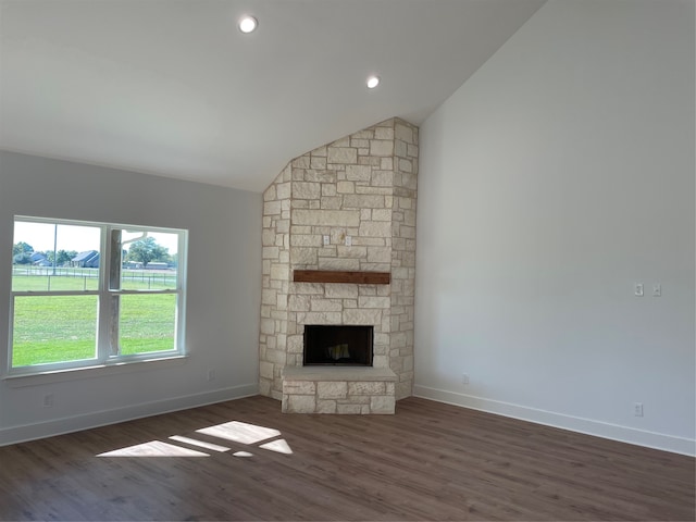 unfurnished living room featuring a stone fireplace, lofted ceiling, and dark hardwood / wood-style floors