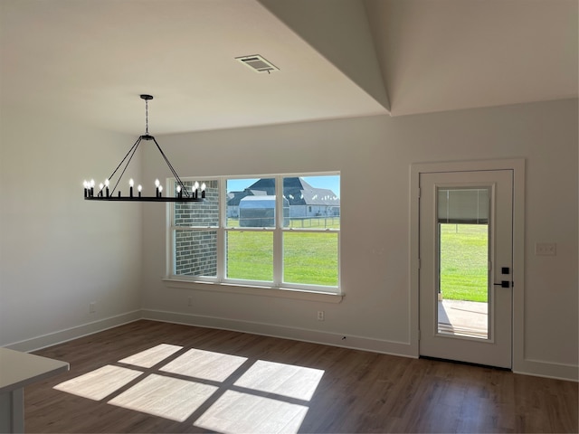 unfurnished dining area featuring a chandelier and dark wood-type flooring