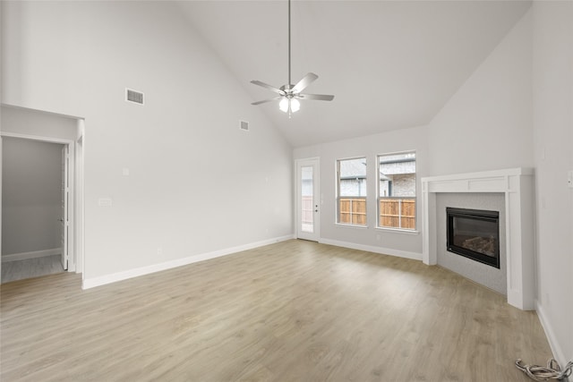 unfurnished living room featuring light wood finished floors, visible vents, ceiling fan, and a glass covered fireplace