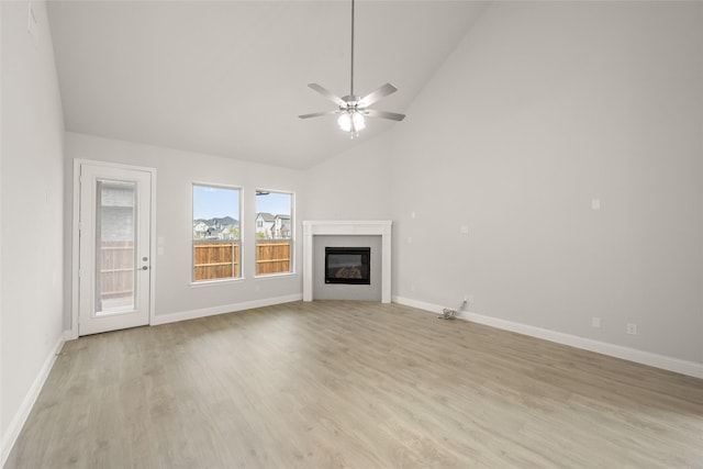 unfurnished living room featuring light wood-type flooring, high vaulted ceiling, a ceiling fan, a glass covered fireplace, and baseboards