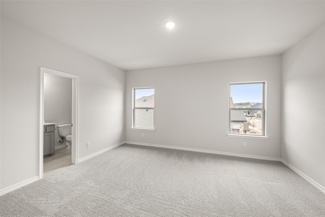 empty room with baseboards, plenty of natural light, and light colored carpet