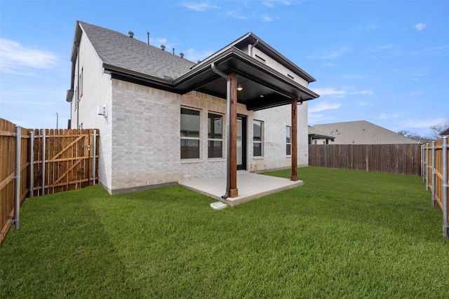 back of house featuring a lawn, a patio, a fenced backyard, roof with shingles, and brick siding