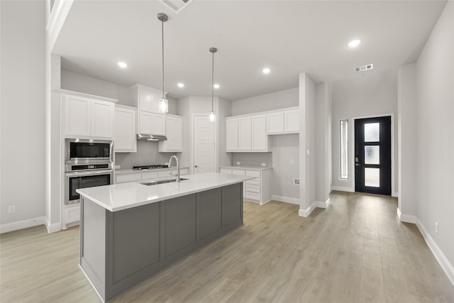 kitchen with visible vents, a sink, decorative backsplash, under cabinet range hood, and appliances with stainless steel finishes