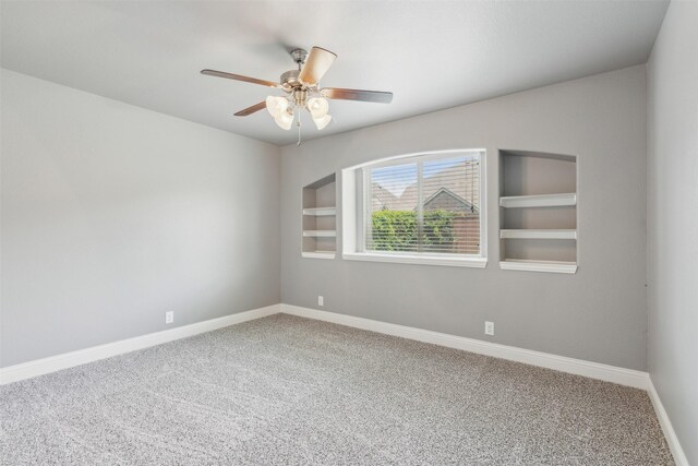 unfurnished room with built in shelves, ceiling fan, and carpet floors