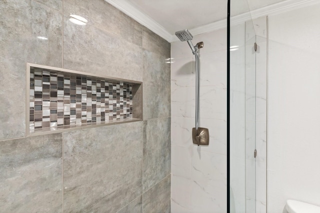 bathroom with a tile shower, crown molding, and toilet