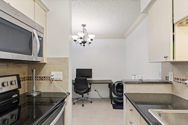 kitchen with appliances with stainless steel finishes, a chandelier, a textured ceiling, light tile patterned floors, and ornamental molding