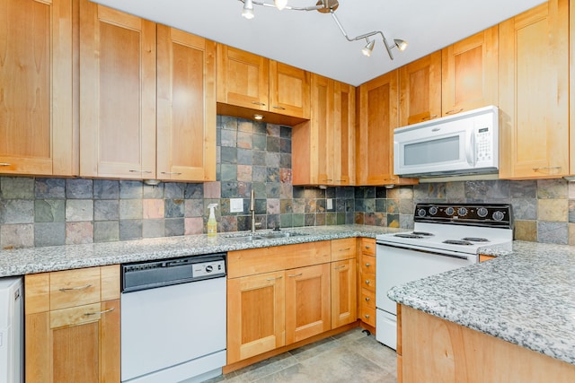 kitchen with sink, decorative backsplash, rail lighting, white appliances, and light stone counters