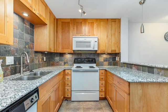 kitchen featuring light stone countertops, white appliances, decorative light fixtures, and sink