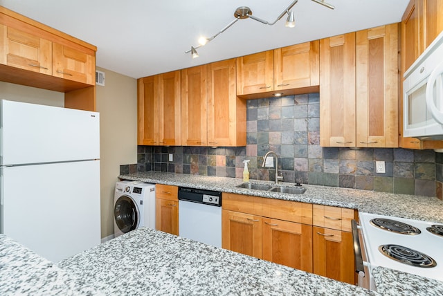 kitchen featuring sink, washer / dryer, white appliances, backsplash, and light stone counters