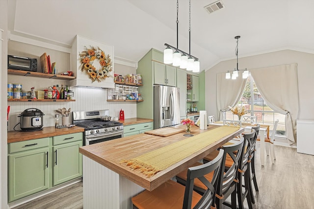 kitchen with stainless steel appliances, green cabinets, light hardwood / wood-style flooring, pendant lighting, and vaulted ceiling