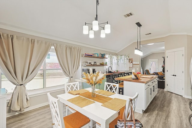 dining area with crown molding, sink, lofted ceiling, and light wood-type flooring