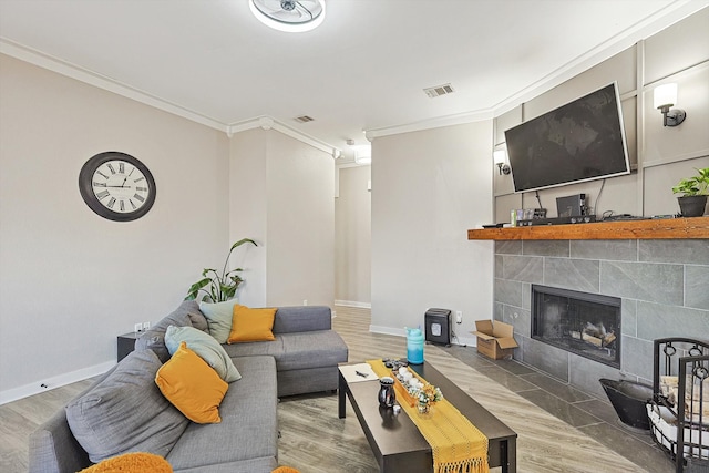 living room with a tile fireplace, hardwood / wood-style floors, and crown molding