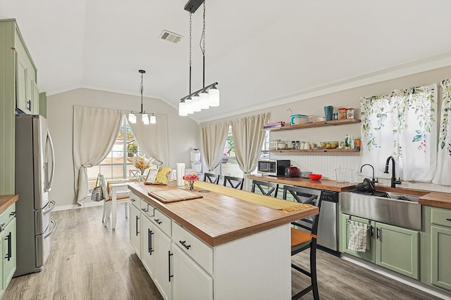 kitchen featuring stainless steel appliances, wooden counters, decorative light fixtures, lofted ceiling, and green cabinetry