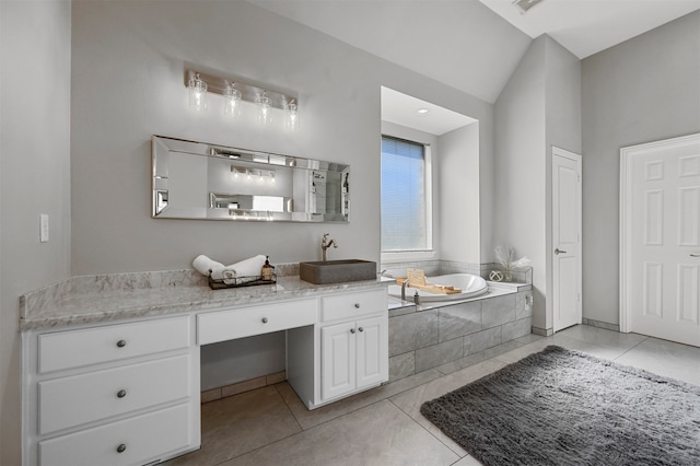 bathroom with tile patterned flooring, vanity, lofted ceiling, and tiled tub