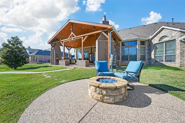 rear view of property with a yard, an outdoor fire pit, and a patio