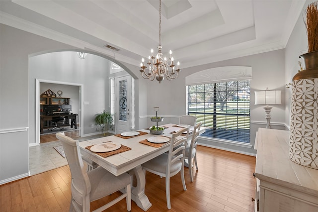 dining area featuring light hardwood / wood-style floors, crown molding, a tray ceiling, and a chandelier