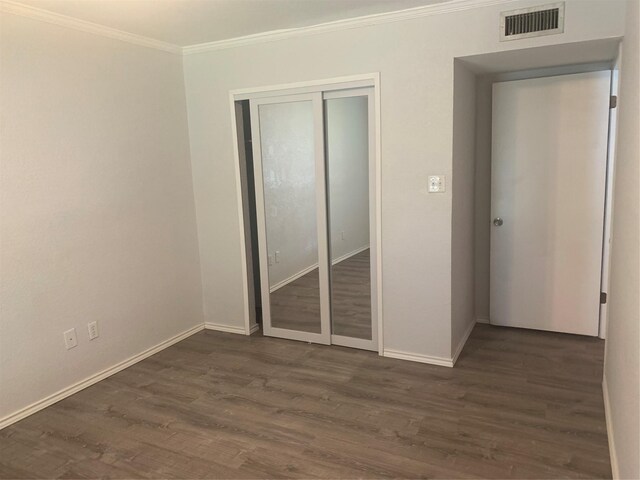 unfurnished bedroom with a closet, dark hardwood / wood-style flooring, and ornamental molding