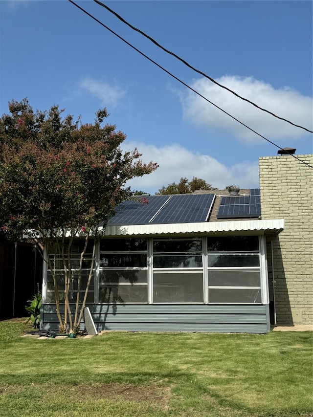 back of house with a lawn and solar panels