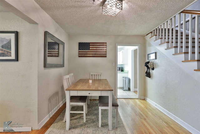 unfurnished dining area featuring light wood-type flooring and a textured ceiling