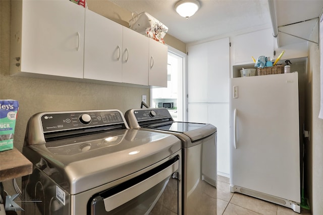 laundry room featuring cabinets, light tile patterned floors, and washing machine and dryer