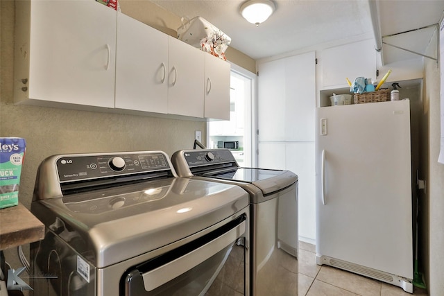 laundry area with washer and dryer, cabinet space, and light tile patterned floors