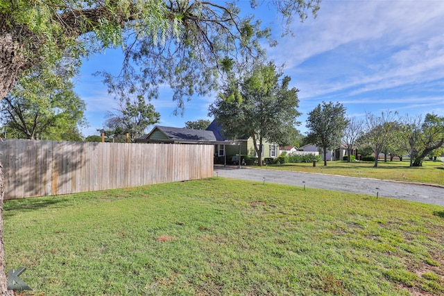 view of yard featuring aphalt driveway and fence