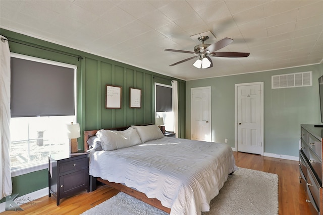 bedroom featuring light hardwood / wood-style flooring, ornamental molding, and ceiling fan