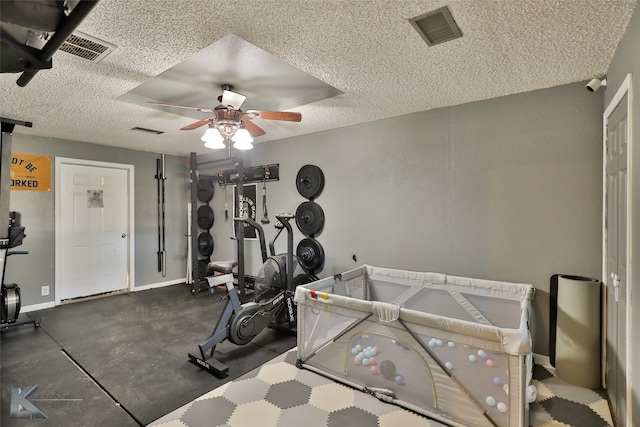 workout room with a textured ceiling and ceiling fan