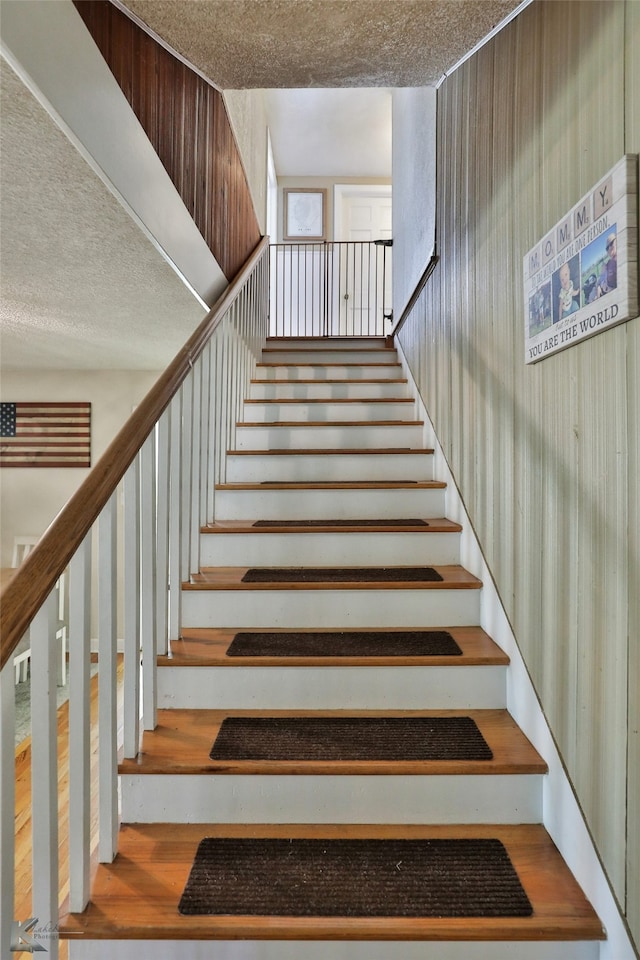 stairs with a textured ceiling and hardwood / wood-style flooring