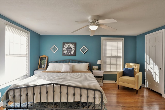 bedroom with hardwood / wood-style flooring, ceiling fan, multiple windows, and a textured ceiling