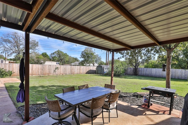 view of patio with outdoor dining area, a fenced backyard, an outdoor structure, and a shed