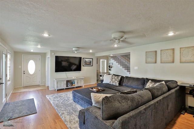 living room featuring ceiling fan, wood-type flooring, and a textured ceiling