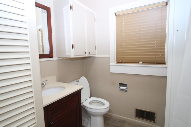 231 N 3rd Ave, Munday, TX 76371 - half bathroom featuring vanity, toilet, and tile walls