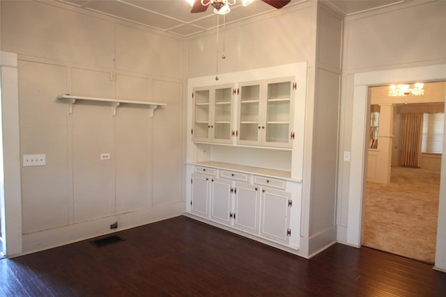 231 N 3rd Ave, Munday, TX 76371 - unfurnished dining area with a ceiling fan, a decorative wall, dark wood-style flooring, and a chandelier