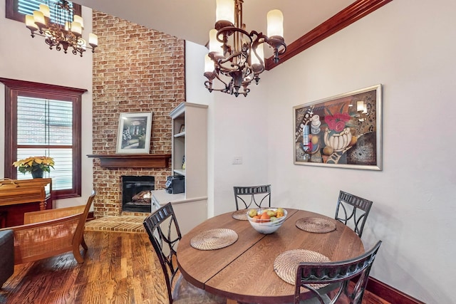 dining room featuring a notable chandelier, wood-type flooring, a fireplace, and lofted ceiling