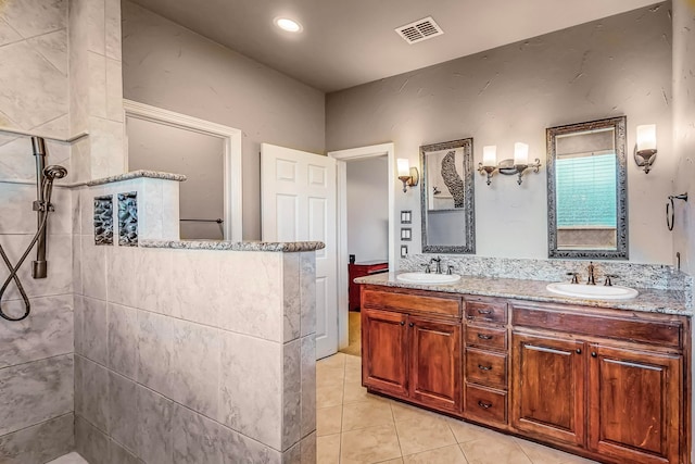 bathroom with a tile shower, vanity, and tile patterned floors