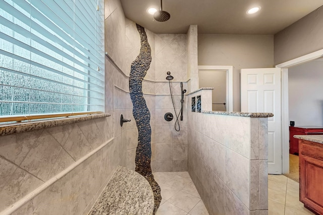 bathroom featuring tile patterned flooring, vanity, and a tile shower