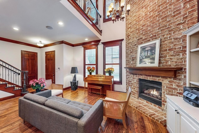 living room featuring a fireplace, light wood-type flooring, crown molding, and a notable chandelier