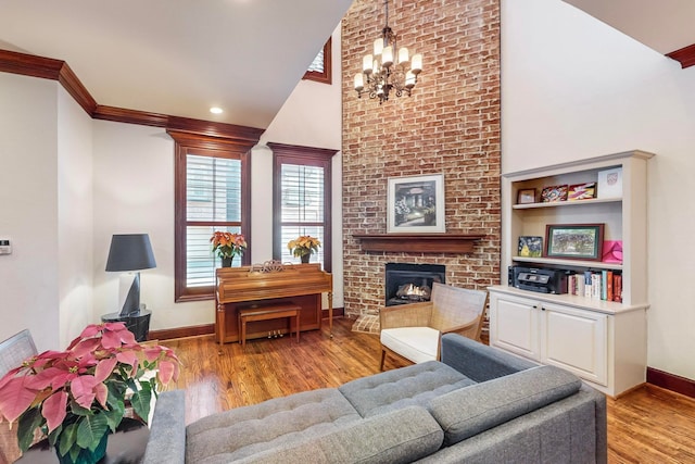 living room with crown molding, a fireplace, a chandelier, and light wood-type flooring