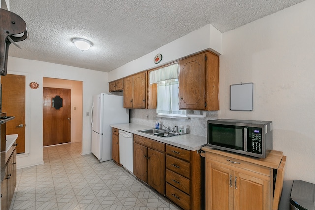 kitchen featuring white appliances, sink, backsplash, and a textured ceiling