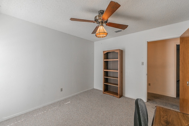 unfurnished office featuring ceiling fan, light colored carpet, and a textured ceiling